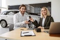 Happy Caucasian young man sitting at table and receives keys of SUV car. Royalty Free Stock Photo