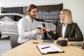 Happy Caucasian young man sitting at table and receives keys of SUV car. Royalty Free Stock Photo