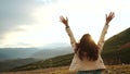 Happy celebrating winning success woman at sunset or sunrise standing elated with arms raised up above her head in