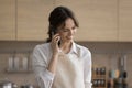 Happy cellphone user adult girl wearing apron, talking on phone