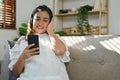 Happy Asian pregnant woman wearing headphones, listening to music while resting in living room Royalty Free Stock Photo