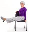 Happy charming beautiful elderly woman doing exercises at home on a chair. Workout gymnastics for health. On a white background Royalty Free Stock Photo