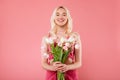 Happy charming blonde lady holding bouquet of flowers, enjoy women day or birthday, smiling at camera, pink background Royalty Free Stock Photo