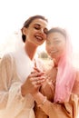 Happy charming bride in a white dress with white veil and a bridesmaid in a beige dress with pink veil hugging tenderly Royalty Free Stock Photo