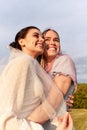 A happy charming bride in a white dress with a white veil and a bridesmaid with a pink veil gently hugging and smiling Royalty Free Stock Photo