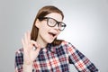 Happy charming teenage girl in glasses showing ok sign