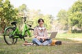 A happy young Asian woman is working remotely in a green park, using her laptop computer Royalty Free Stock Photo