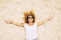 Happy and cheerful adult caucasian lady lay down on the sand at the beach enjoying freedom and healthy lifestyle in the nature -