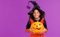 Happy cheerful ethnic girl in a pumpkin costume celebrates Halloween and laughs on a bright purple background