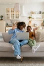 Happy cheerful African American mother and son sit on sofa with laptop waving hands at webcam Royalty Free Stock Photo