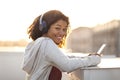 Happy cheerful african american woman in headphones listening to music on smartphone at rooftop Royalty Free Stock Photo