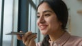 Happy cheerful Arabian Indian business girl talk mobile phone near window female businesswoman woman say on speakerphone Royalty Free Stock Photo
