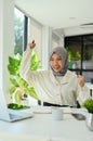 Happy and cheerful Asian Muslim female office worker hands up, celebrating her success Royalty Free Stock Photo