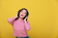 Happy cheerful Beautiful Asian woman wearing wireless headphones enjoying listening to music on yellow background.People lifestyle Royalty Free Stock Photo