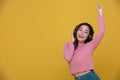 Happy cheerful Beautiful Asian woman wearing wireless headphones enjoying listening to music on yellow background.People lifestyle Royalty Free Stock Photo