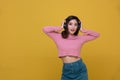 Happy cheerful Beautiful Asian woman wearing wireless headphones enjoying listening to music on yellow background.People lifestyle Royalty Free Stock Photo