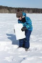 Happy cheerful boy lifting snow block for building an igloo