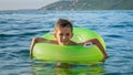 Happy cheerful boy splashing water while swimming in inflatable ring at the sea. Family holidays, vacations, summertime Royalty Free Stock Photo