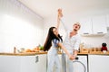 Happy cheerful Caucasian couple dancing together in the kitchen, spending time together. Energetic and fun relationship dance. Royalty Free Stock Photo