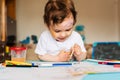 Happy cheerful child drawing with brush in album using a lot of painting tools. Royalty Free Stock Photo