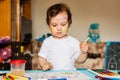 Happy cheerful child drawing with brush in album using a lot of painting tools. Royalty Free Stock Photo