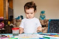 Happy cheerful child draws with a brush in an album using multi-colored paints Royalty Free Stock Photo