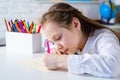 Happy cheerful child girl drawing. Creativity concept. Cute child drawing using felt-tip pen while sitting at table.