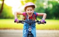 Happy cheerful child girl riding a bike in Park in nature