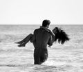 Happy cheerful couple having fun hugging running in the sea together. Romantic vacation, honeymoon love Royalty Free Stock Photo