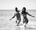 Happy cheerful couple hold hans and running in the sea together. Romantic vacation, honeymoon love Royalty Free Stock Photo