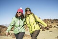 Happy cheerful couple of middle age women friends walking together at the mountain for alternative vacation - sunny day in outdoor