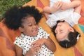 Happy cheerful dark skin girls and caucasian girls laying on mat at outdoors park, Her smiling and laughing together, Relationship Royalty Free Stock Photo