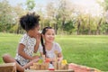 Happy cheerful ethnic girls play wooden block puzzle together at outdoors park, Black girl whisper secret to white girl. , Royalty Free Stock Photo