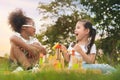 Happy cheerful ethnic girls play wooden block puzzle together at outdoors park, children wear glasses, Relationship little kids, Royalty Free Stock Photo