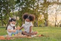 Happy cheerful ethnic girls play wooden block puzzle together at outdoors park , They wear masks to protect them from virus, Royalty Free Stock Photo