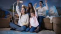 Happy cheerful family celebrating victory or football goal while watching TV at night. Royalty Free Stock Photo