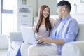 Happy cheerful family couple resting on sofa in living room searching internet  on laptop Royalty Free Stock Photo