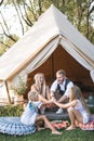 Happy cheerful family, father, mother and two daughters, putting their hands together, while sitting near the big wigwam Royalty Free Stock Photo