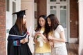 Happy and cheerful Female university graduate students in academic dress chat with friends who came to congratulate on Royalty Free Stock Photo