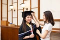 Happy and cheerful Female university graduate students help each other to put on academic dress gown and cap or tam on