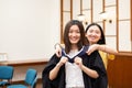 Happy and cheerful Female university graduate students help each other to put on academic dress gown and cap or tam on Royalty Free Stock Photo