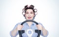 Happy cheerful girl in curlers with steering wheel. Front view. Housewife driving a car.