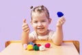A happy, cheerful girl with doll knitted hats on her hands. A little girl is sitting at a table and playing finger theater games w Royalty Free Stock Photo