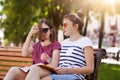 Happy cheerful girls are in the park to enjoy summer atmosphere and read latest news in world. Young beautiful friends give funny Royalty Free Stock Photo