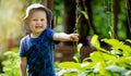 Happy cheerful little boy having fun in garden. playing with plants. smiling and looking on camera Royalty Free Stock Photo