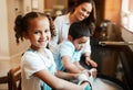 Happy cheerful little mixed race girl helping her mother wash the dishes in the kitchen at home. Hispanic child smiling Royalty Free Stock Photo