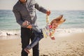 Happy cheerful loving family, father and little daughter playing on beach, young father is holding his kid upside down Royalty Free Stock Photo