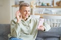 Happy cheerful senior woman having video call with friend or family on smartphone while sitting on sofa at home Royalty Free Stock Photo