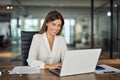 Happy mid aged professional business woman looking at laptop working in office. Royalty Free Stock Photo