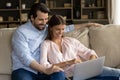 Happy cheerful millennial couple watching video, movie on laptop computer